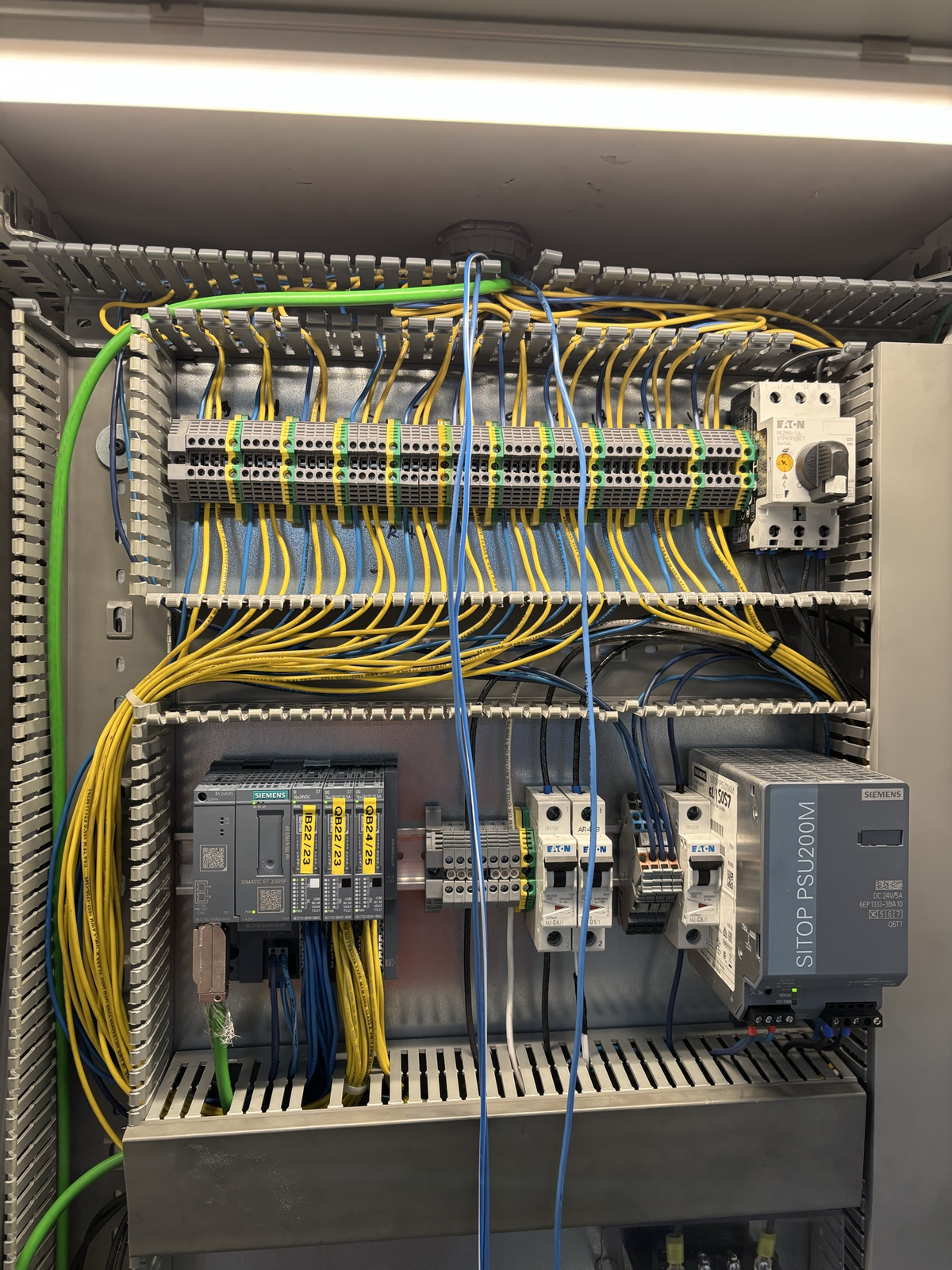 Industrial control panel with labeled terminal blocks, PLC I/O modules, and neatly routed wiring
